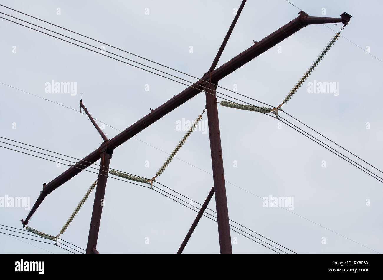 close up of top portion of electric power line tower with cloudy sky Stock Photo