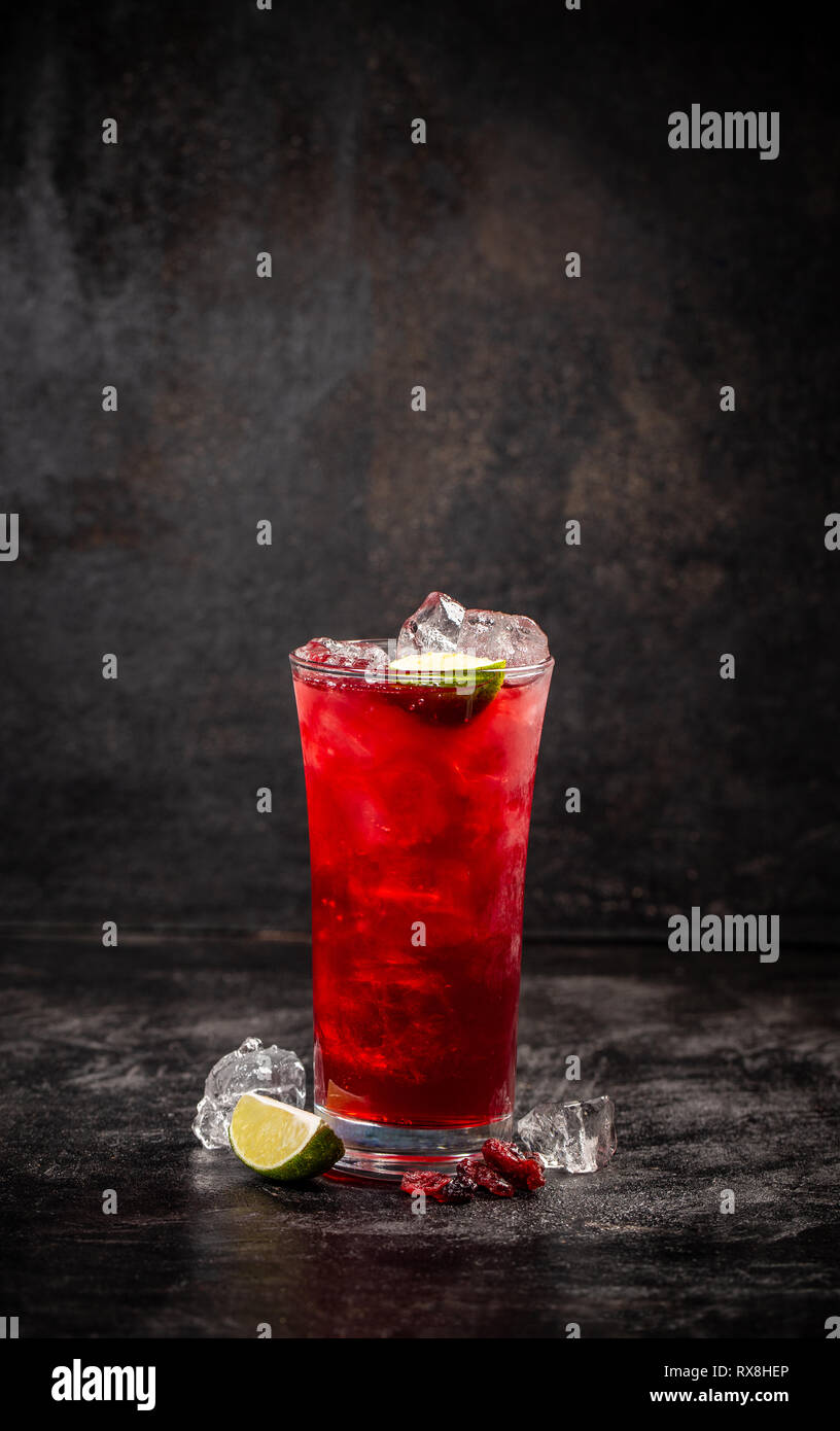 Refreshment alcoholic red cranberry and lime cocktail with ice on dark background, copy space Stock Photo