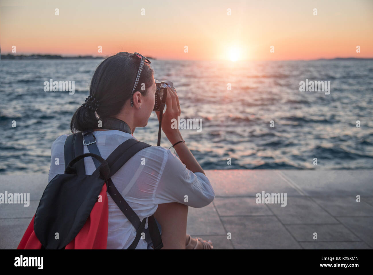 Woman with a camera photographing the sunset on the sea coast Stock ...