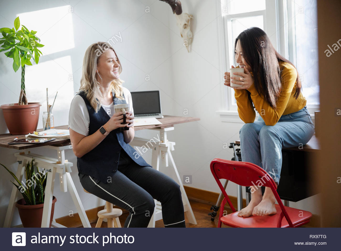 Creative businesswomen talking and drinking coffee in home office Stock Photo