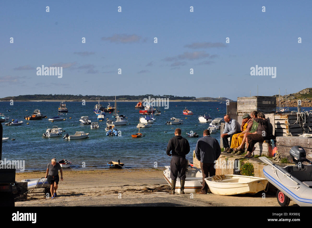 Fisherman resting overlooking the harbour at Hugh Town on St Mary's, Isles of Scilly,full of moored boats in the evening sun. Stock Photo