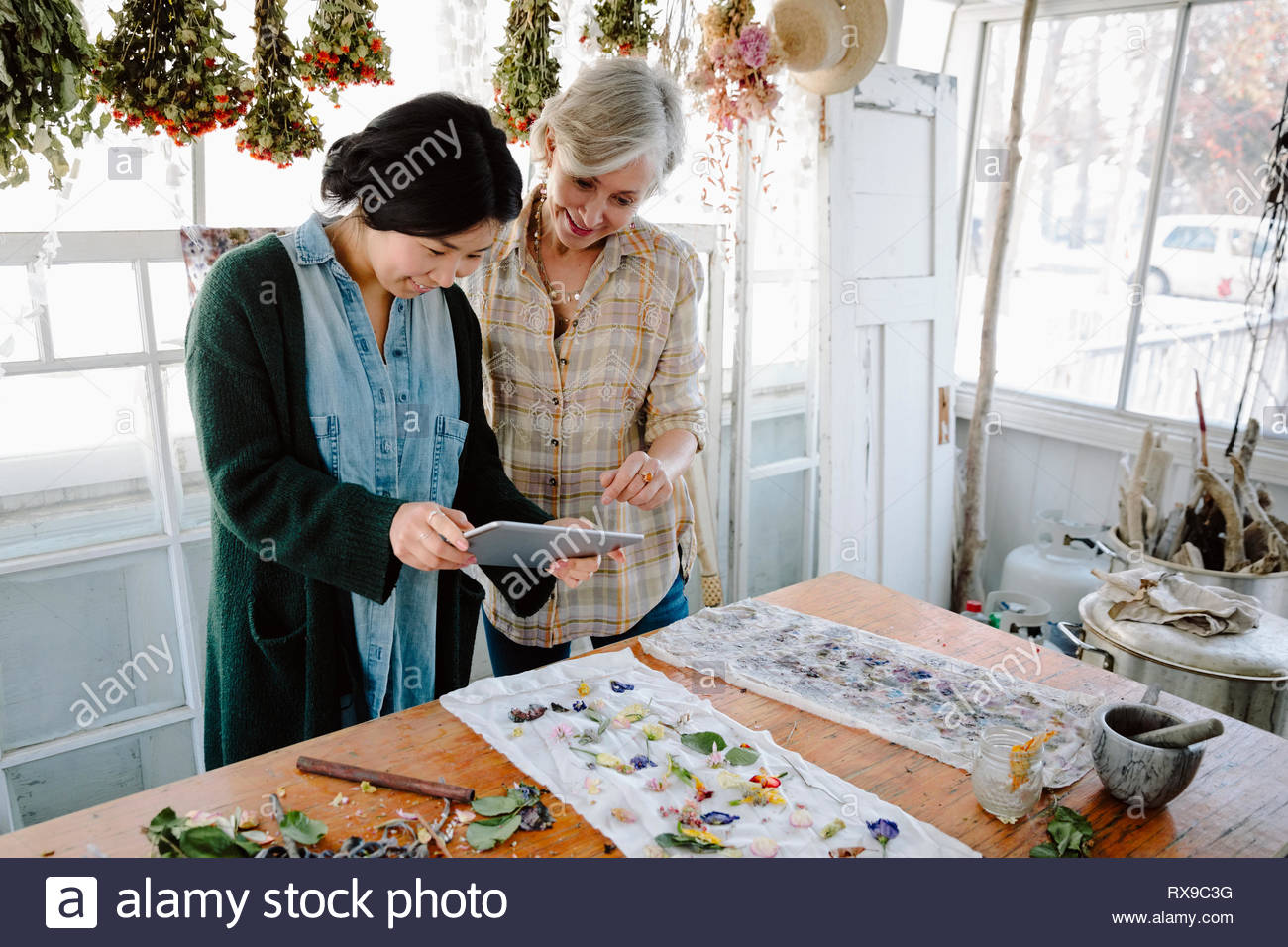 Women with digital tablet drying flowers for paper making Stock Photo