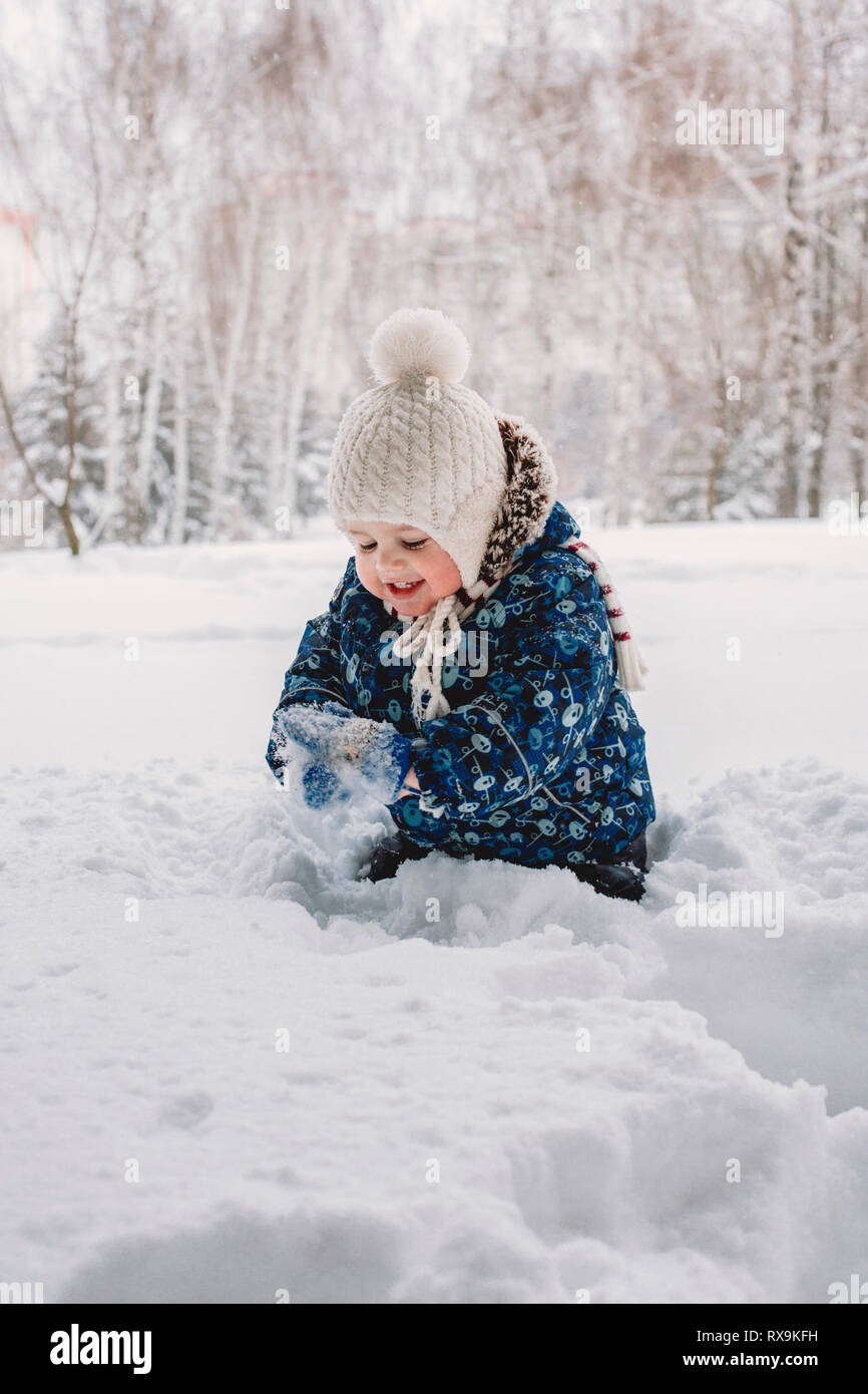 Cute happy baby boy playing with snow while standing on field against trees  in park Stock Photo - Alamy