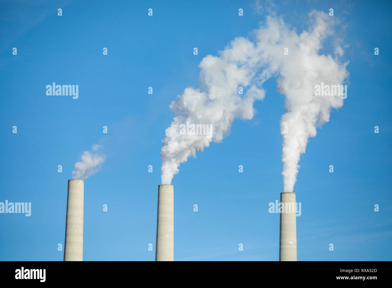 Low angle view of smoke emitting from chimneys against clear blue sky Stock Photo