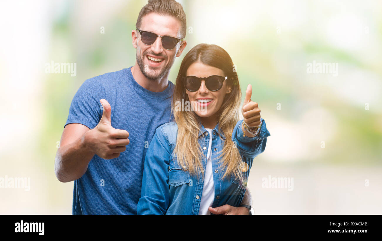 Young couple in love wearing sunglasses over isolated background doing ...