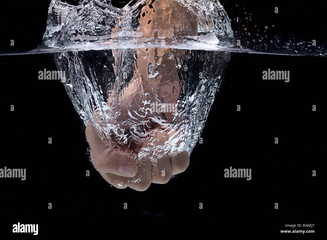 A concept photo of a fist punching into water in a studio setting. Stock Photo