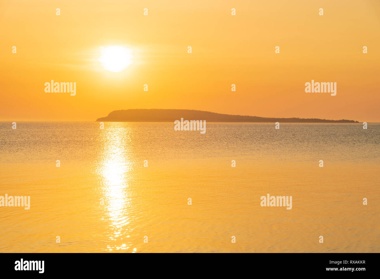 Sun rising through mist over Bear's Rump Island in Georgian Bay turns the sky and water to a beautiful golden colour, Fathom Five National Marine Park, Ontario, Canada Stock Photo