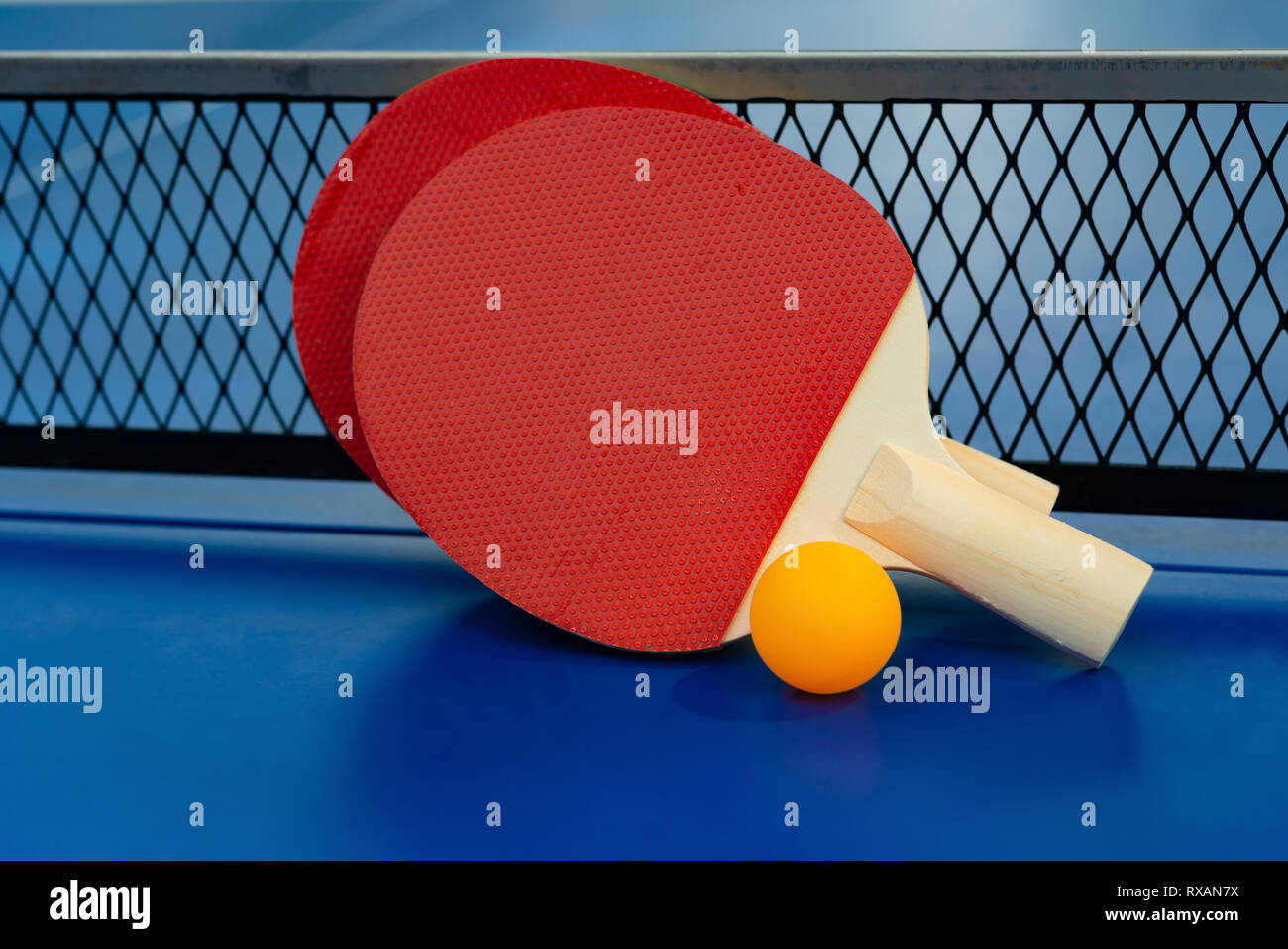 pingpong rackets and ball and net on a blue pingpong table Stock Photo