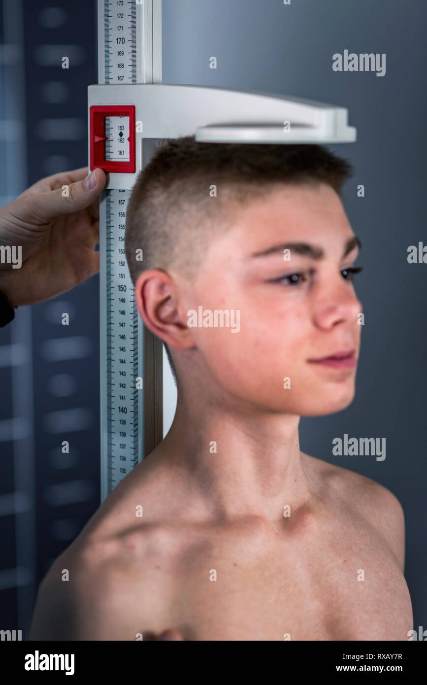 Physical therapist measuring height of teenage boy Stock Photo