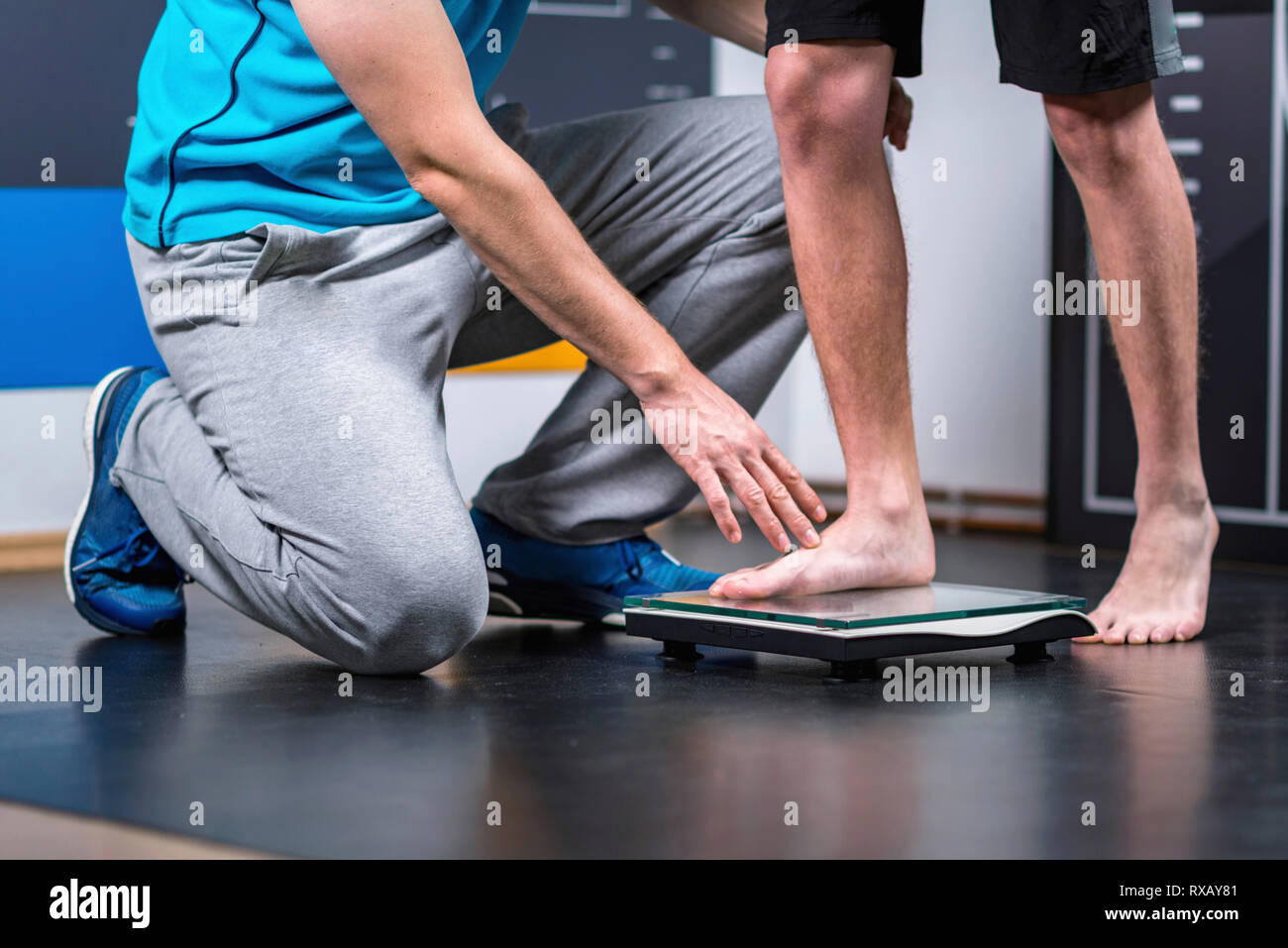 Physical therapist measuring weight of teenage boy Stock Photo