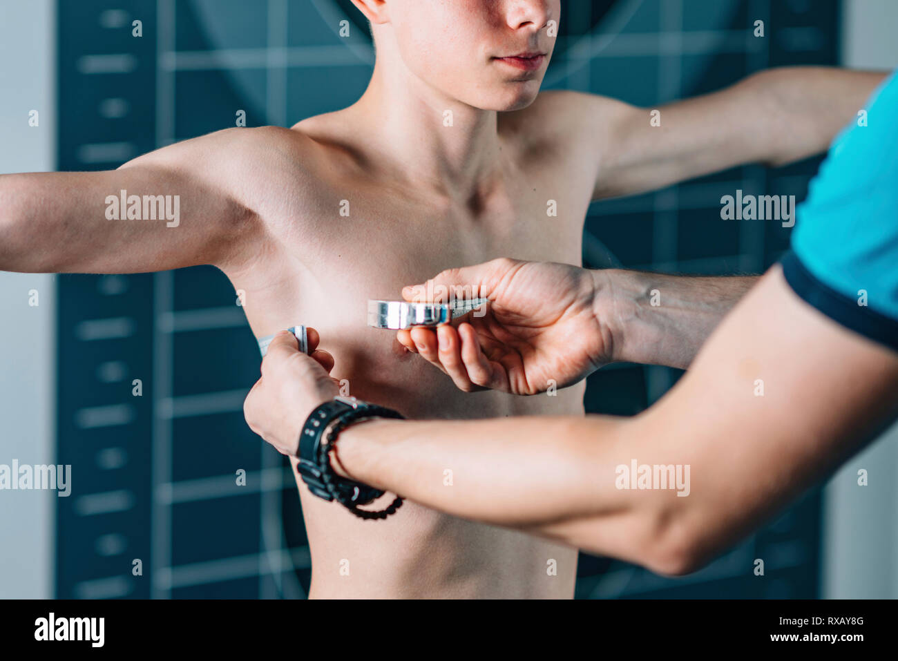 Physical therapist measuring teenage boy's chest Stock Photo