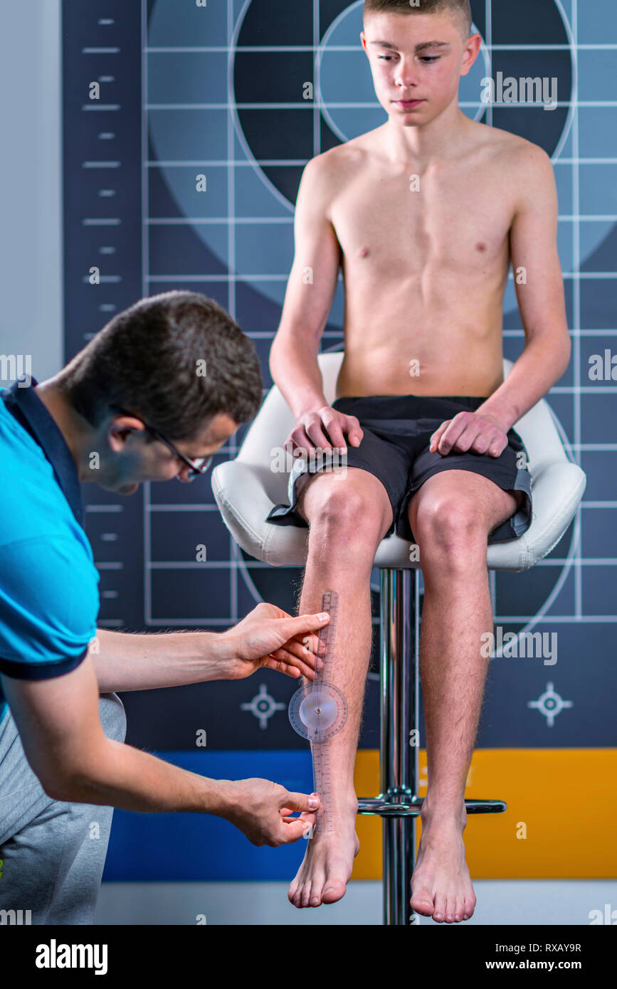 Physical therapist measuring teenage boy's shin Stock Photo