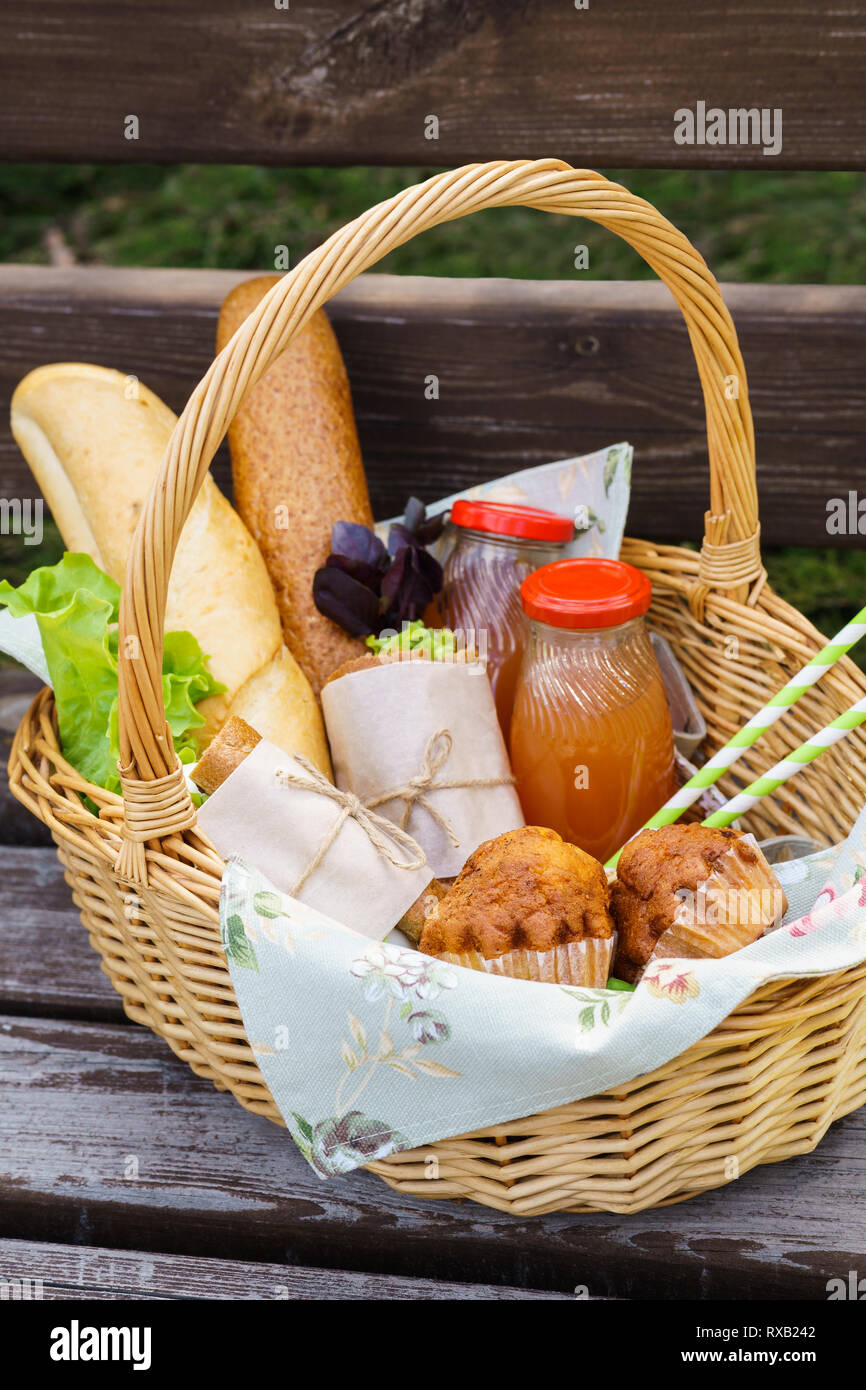 Picnic basket with various food and drinks on a park bench for an ...