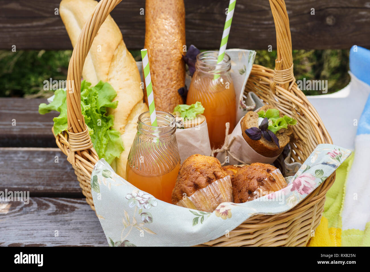 Picnic basket with various food and drinks on a park bench for an ...