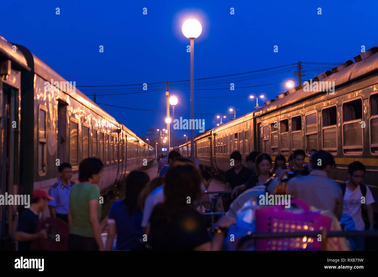 Passengers on a platform with trains either side at Hanoi railway station (Ga Hà Nội) in early morning, Hanoi, Vietnam Stock Photo