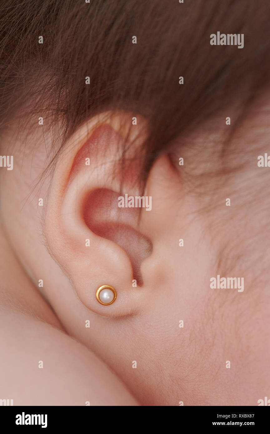Baby ear with gold earring close up view Stock Photo