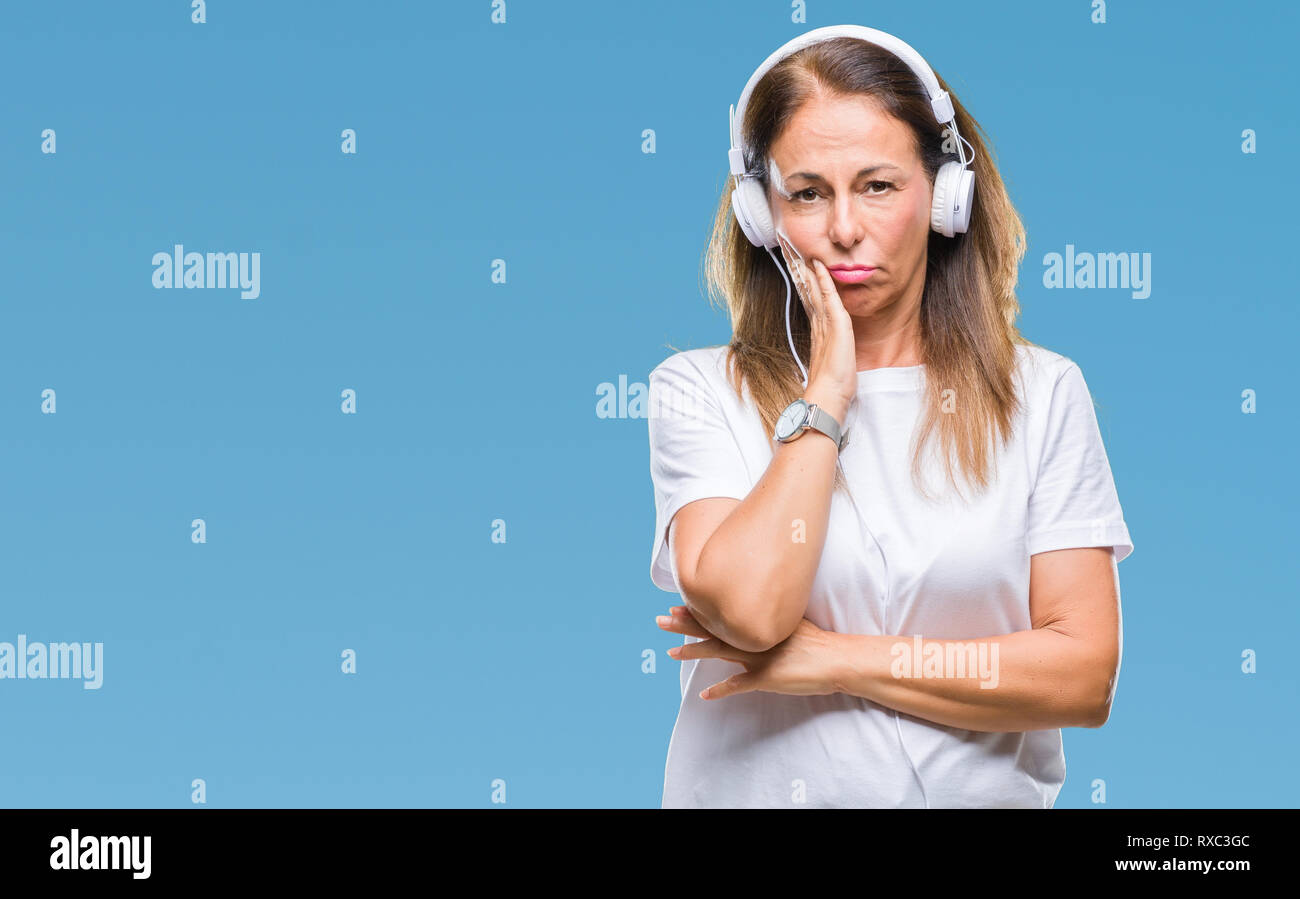 Middle age hispanic woman listening to music wearing headphones over ...