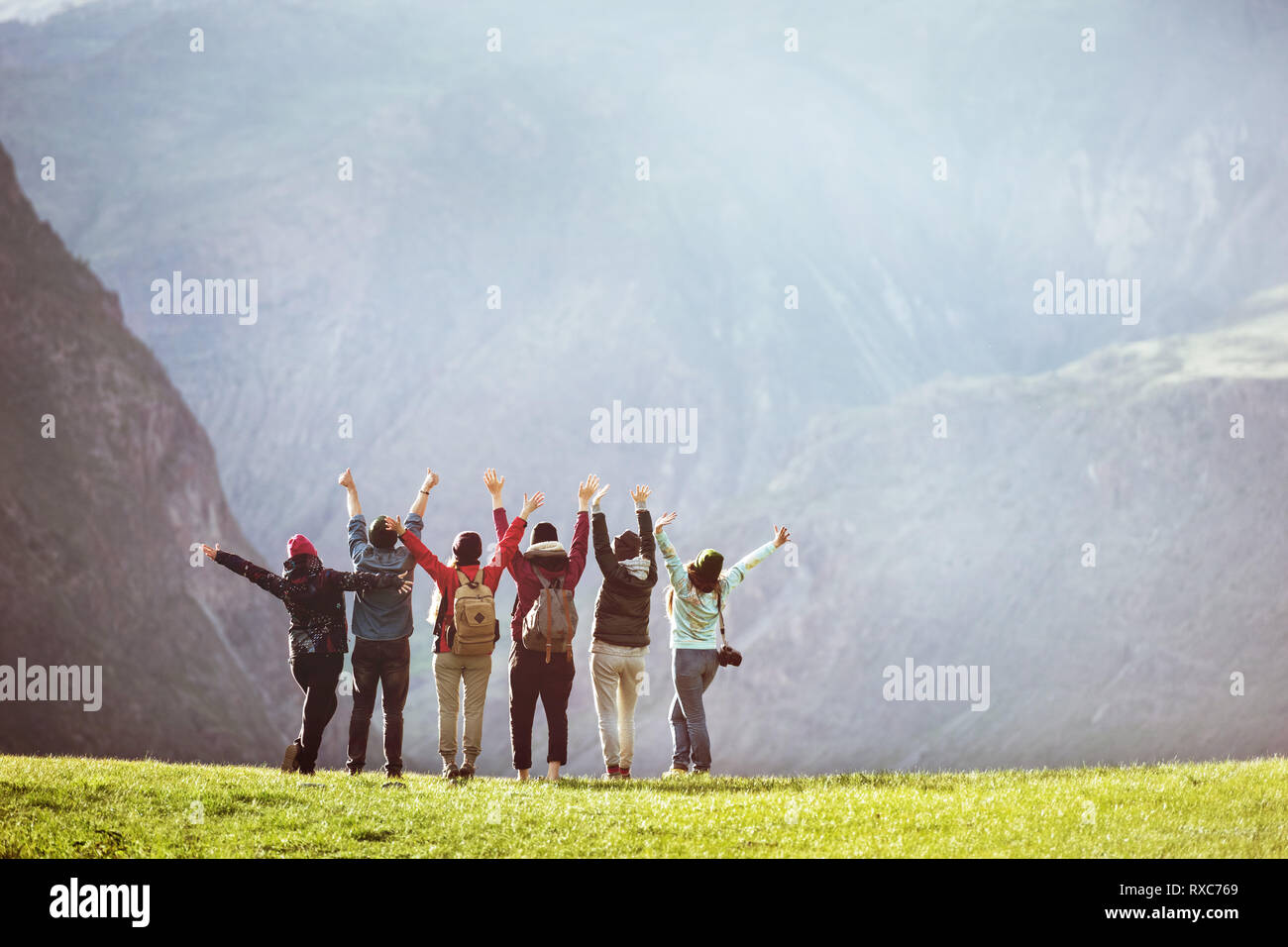 Happy hikers or friends stands against mountain valley with raised arms and having fun. Space for text Stock Photo