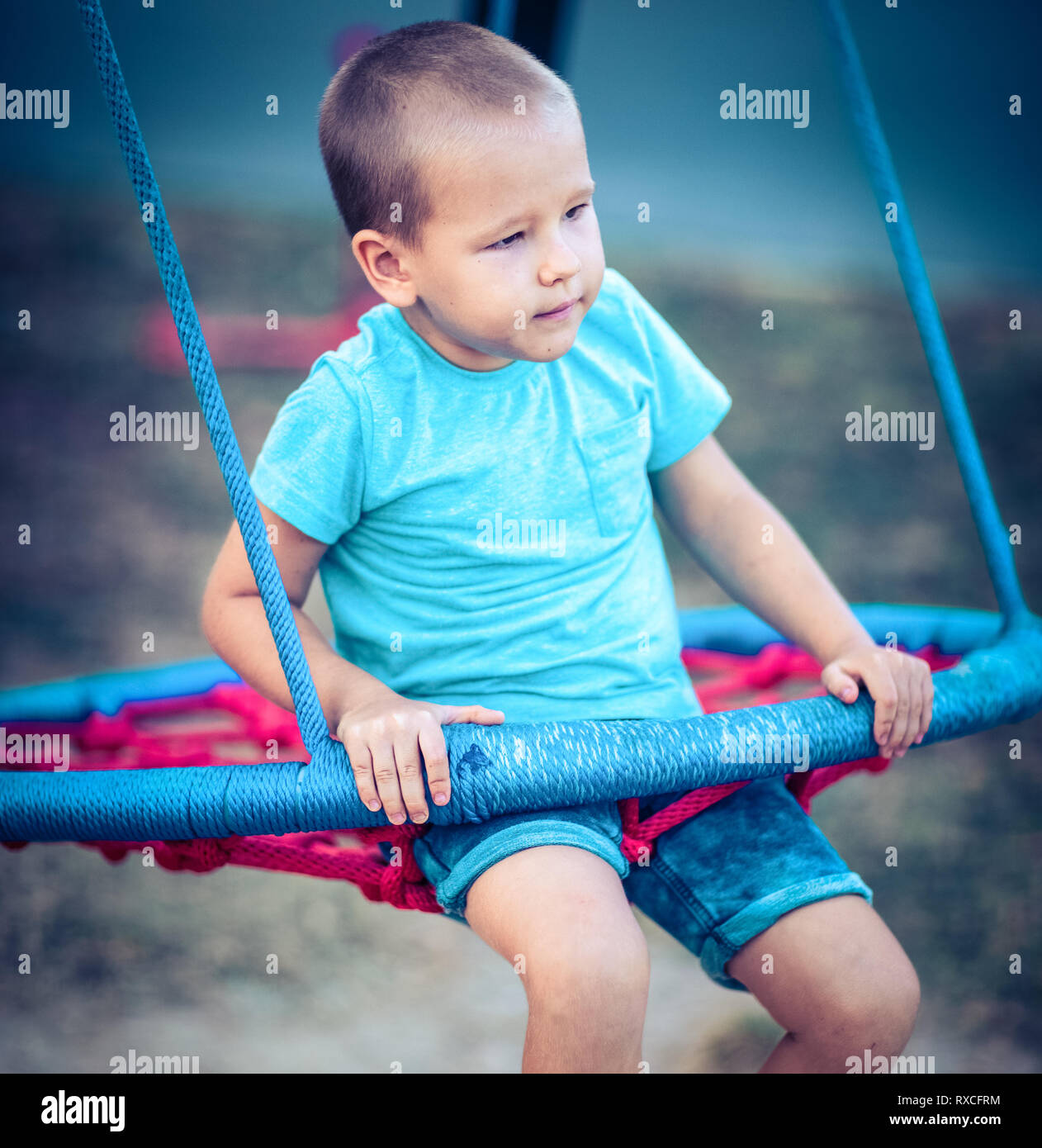 Little boy swinging on a swing at kids playground outdoor Stock Photo