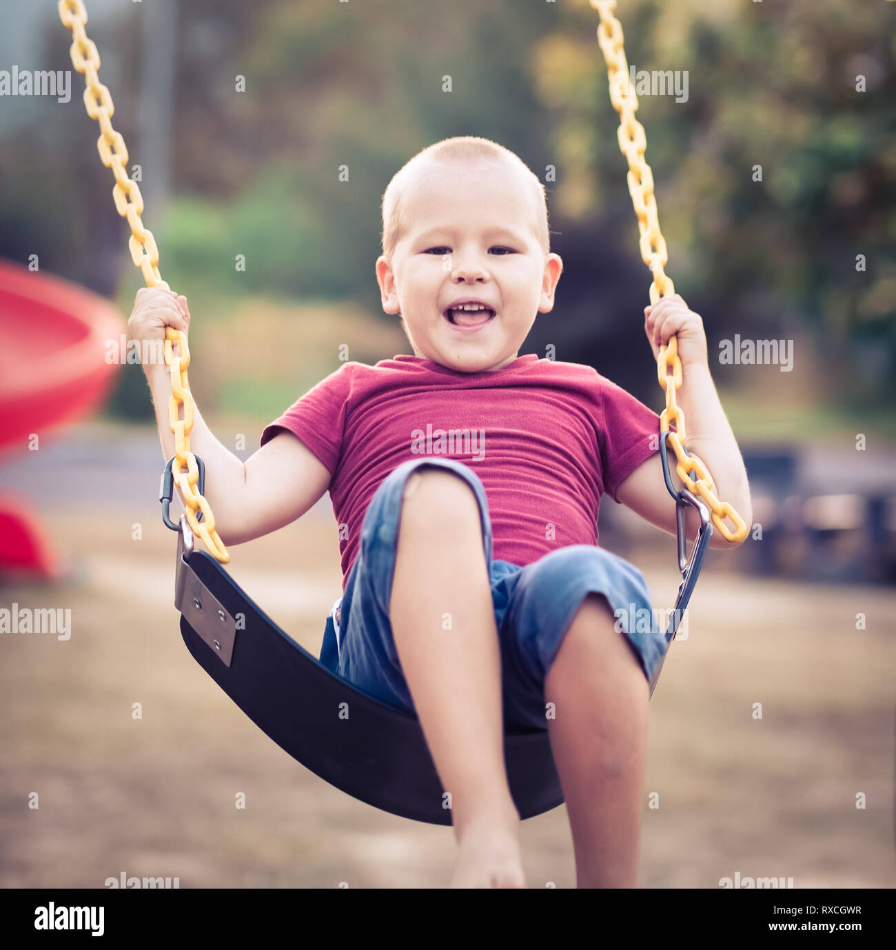 Little boy swinging on a swing at kids playground outdoor Stock Photo