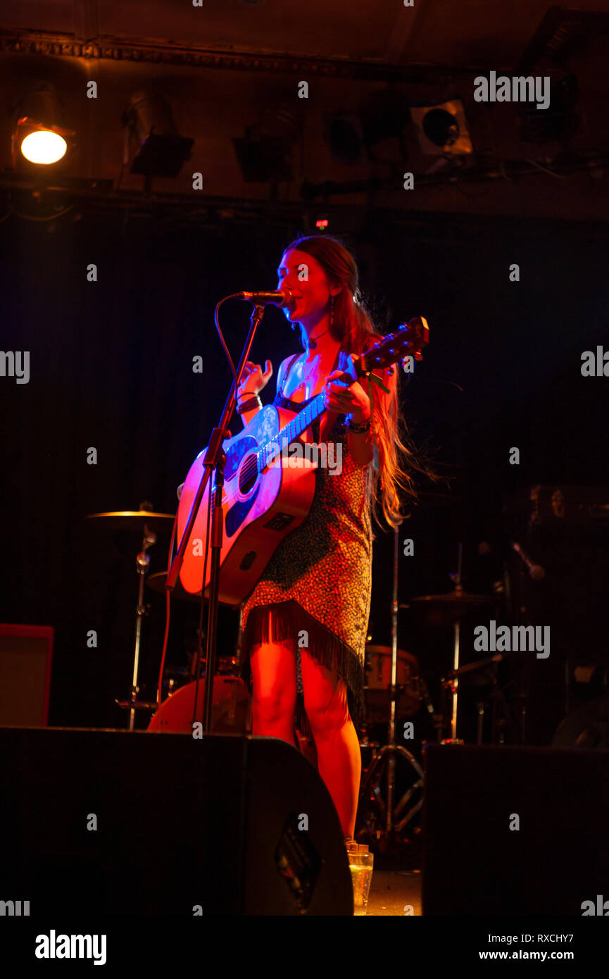 Female singer with acoustic guitar playing on stage Stock Photo - Alamy