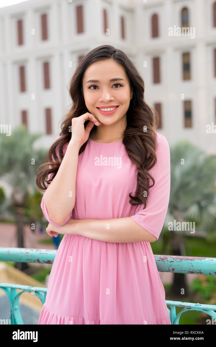 Young beautiful stylish girl in pink dress walking and posing between ...