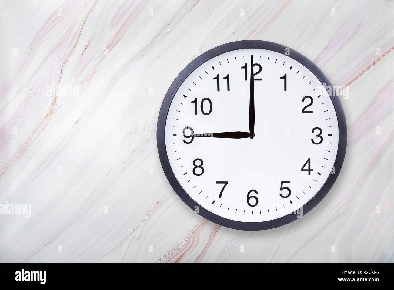 Wall clock show nine o'clock on marble texture. Office clock show 9pm or 9am Stock Photo