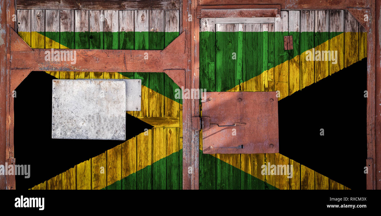 Closeup of an old warehouse gate with the national flag of Jamaica. The concept of export