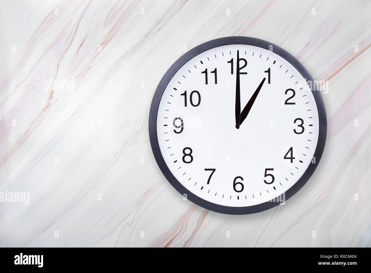 Wall clock on marble texture show one o'clock. Office clock show 1pm or