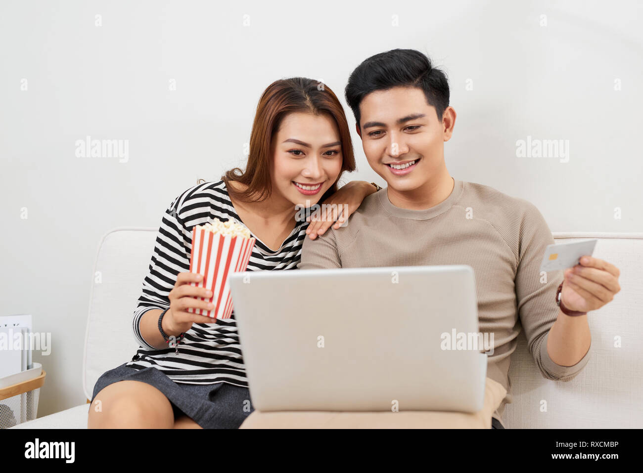 Young couple surfing on internet with laptop. Modern white apartment in background Stock Photo