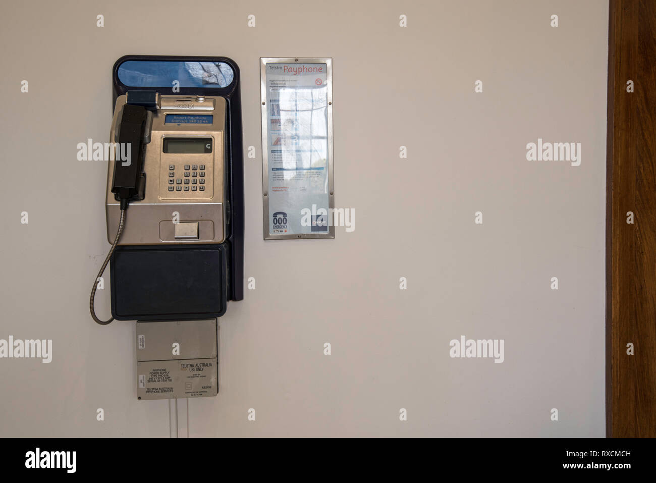 A Telstra payphone mounted on an interior wall at the Mitchell Library in Sydney, Australia Stock Photo