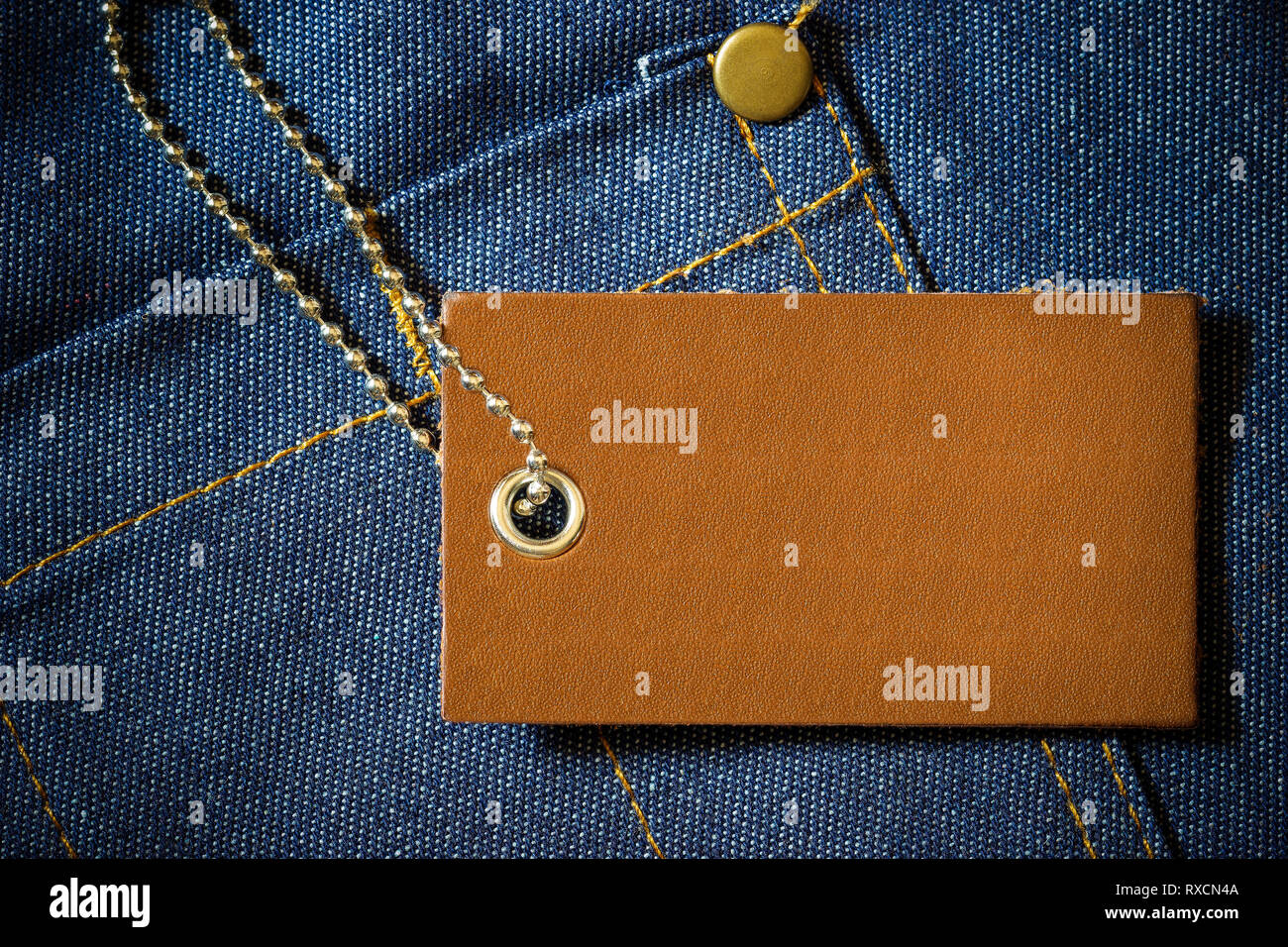 Leather label of product price and stainless steel ball chain on denim clothing. The concept of Fashion jeans. Stock Photo