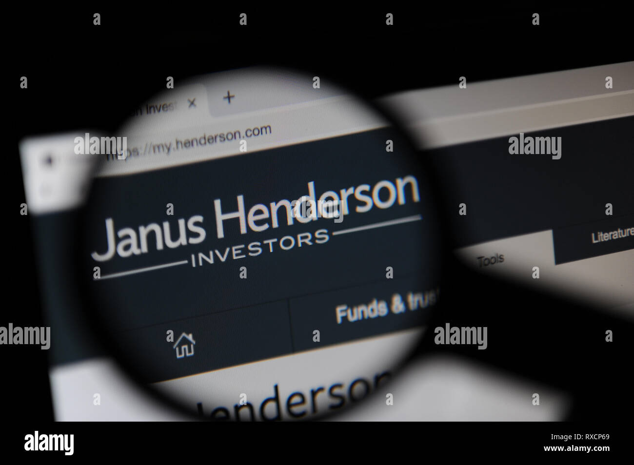The Janus Henderson website is seen through a magnifying glass. Janus