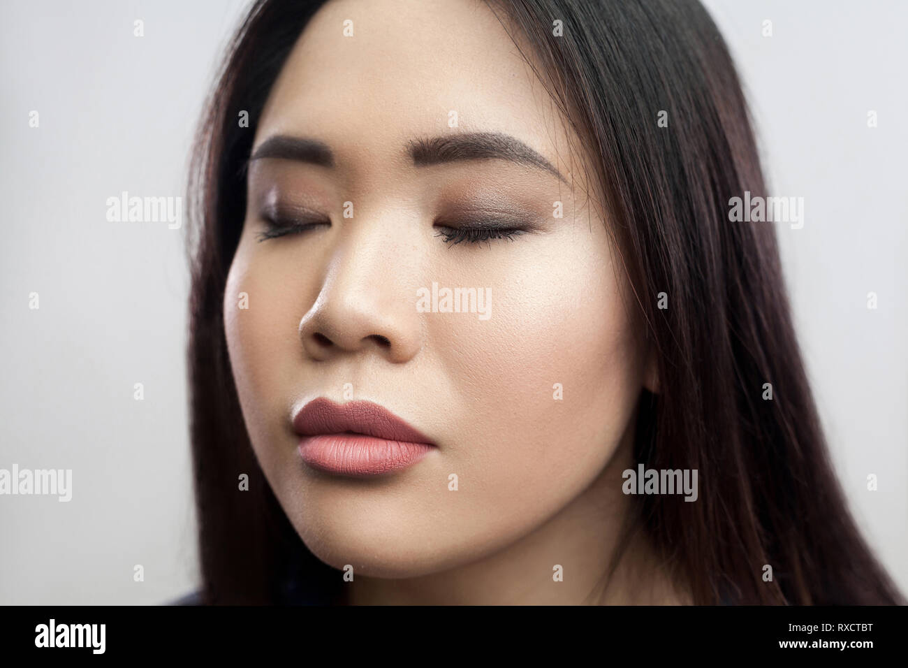 Closeup beauty portrait of calm beautiful brunette asian young woman with  makeup, straight dark hair standing with closed eyes and relaxed face.  indoo Stock Photo - Alamy