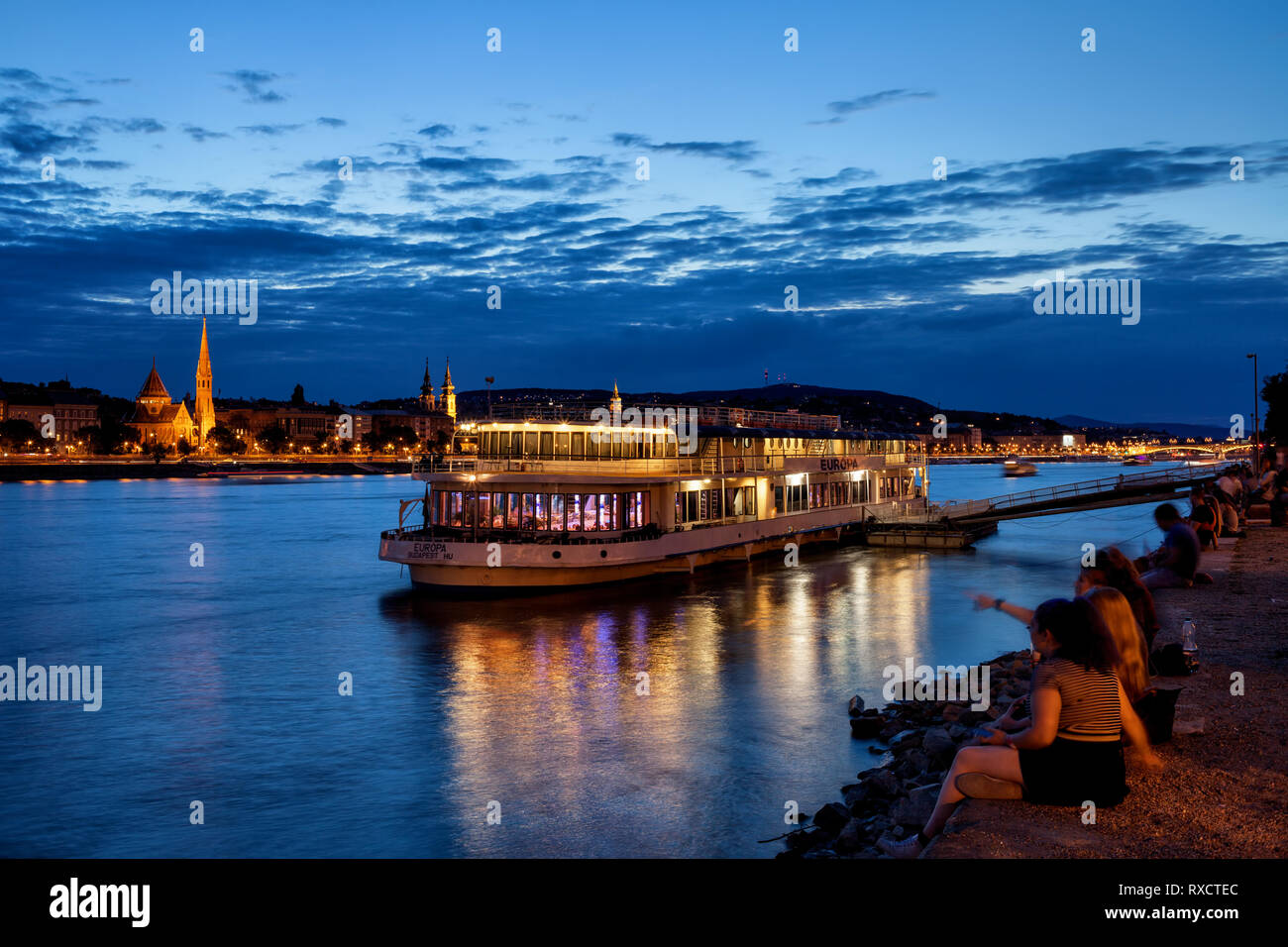Hungary, city of Budapest, people hangout at Danube River waterfront on tranquil evening, cruise and dinner boat, view from Pest to Buda side. Stock Photo