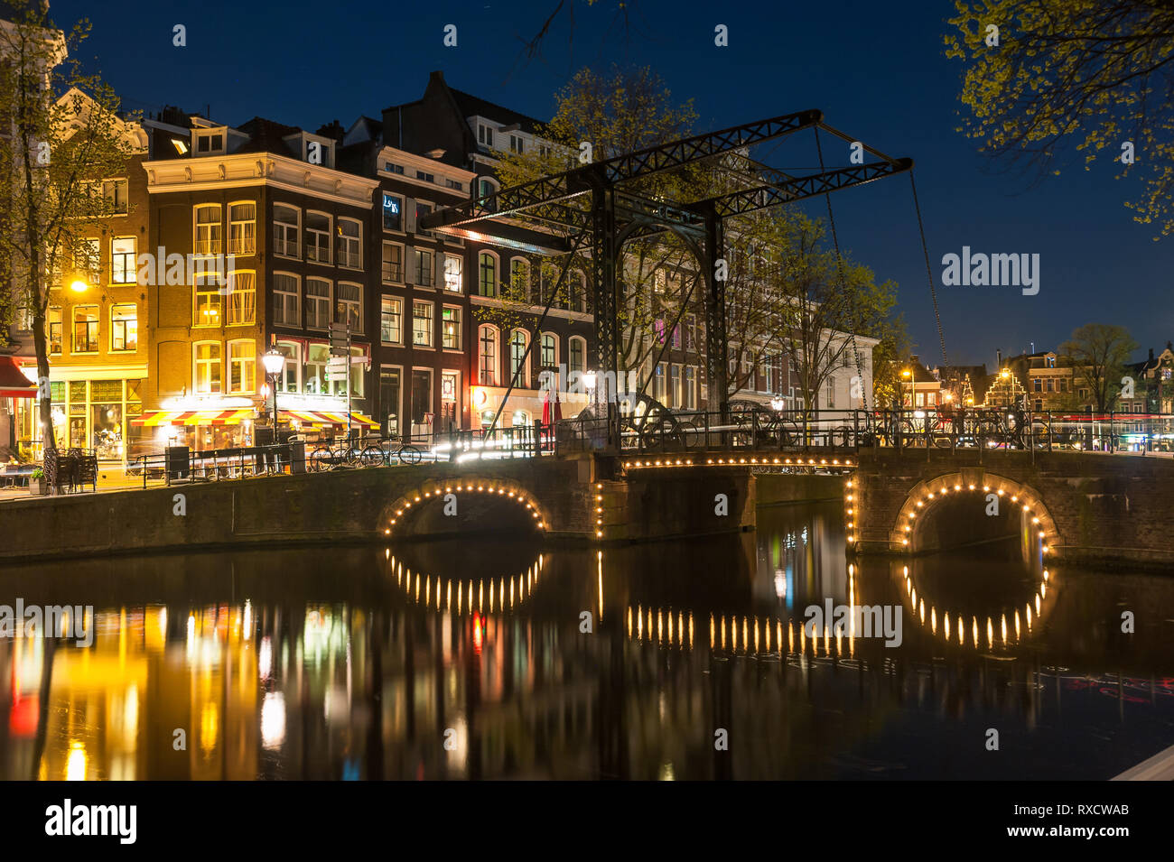 Night landscape with houses and canal in Amsterdam, light reflection in water, cityscape Stock Photo