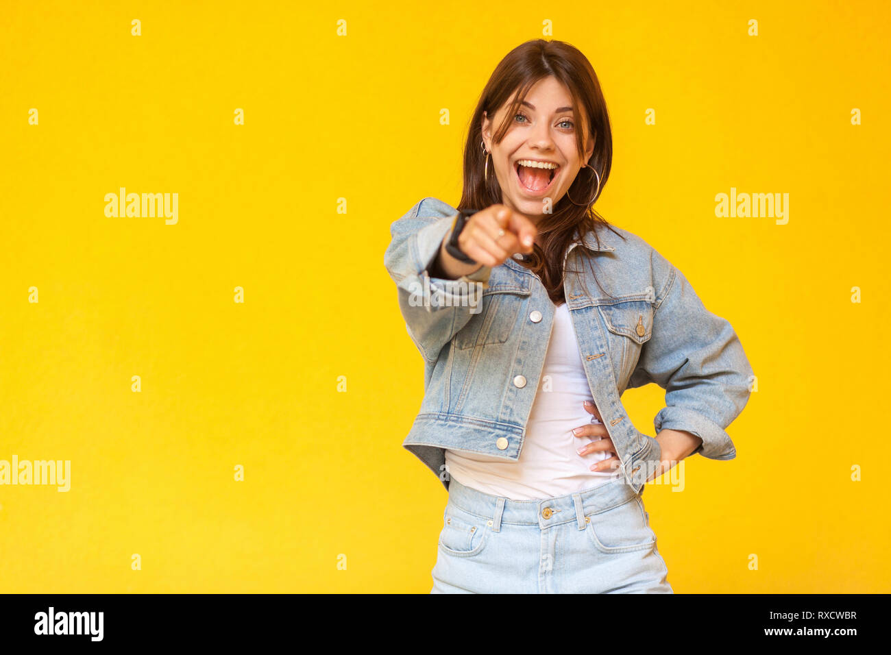 Portrait of suprised beautiful brunette young woman with makeup in denim casual style standing, pointing and looking at camera with amazed face. indoo Stock Photo