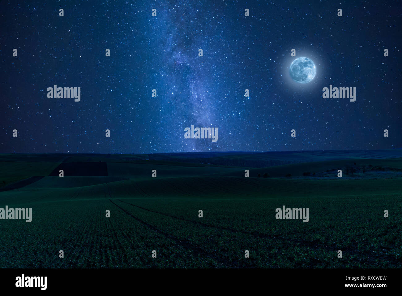 Nidht landscape with green fields on hills and moon, stars in sky over farmland Stock Photo