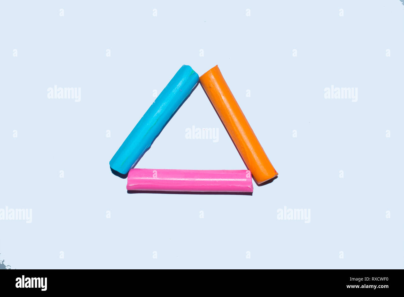 Colorful clay sticks forming a traingle shape on a white background Stock Photo