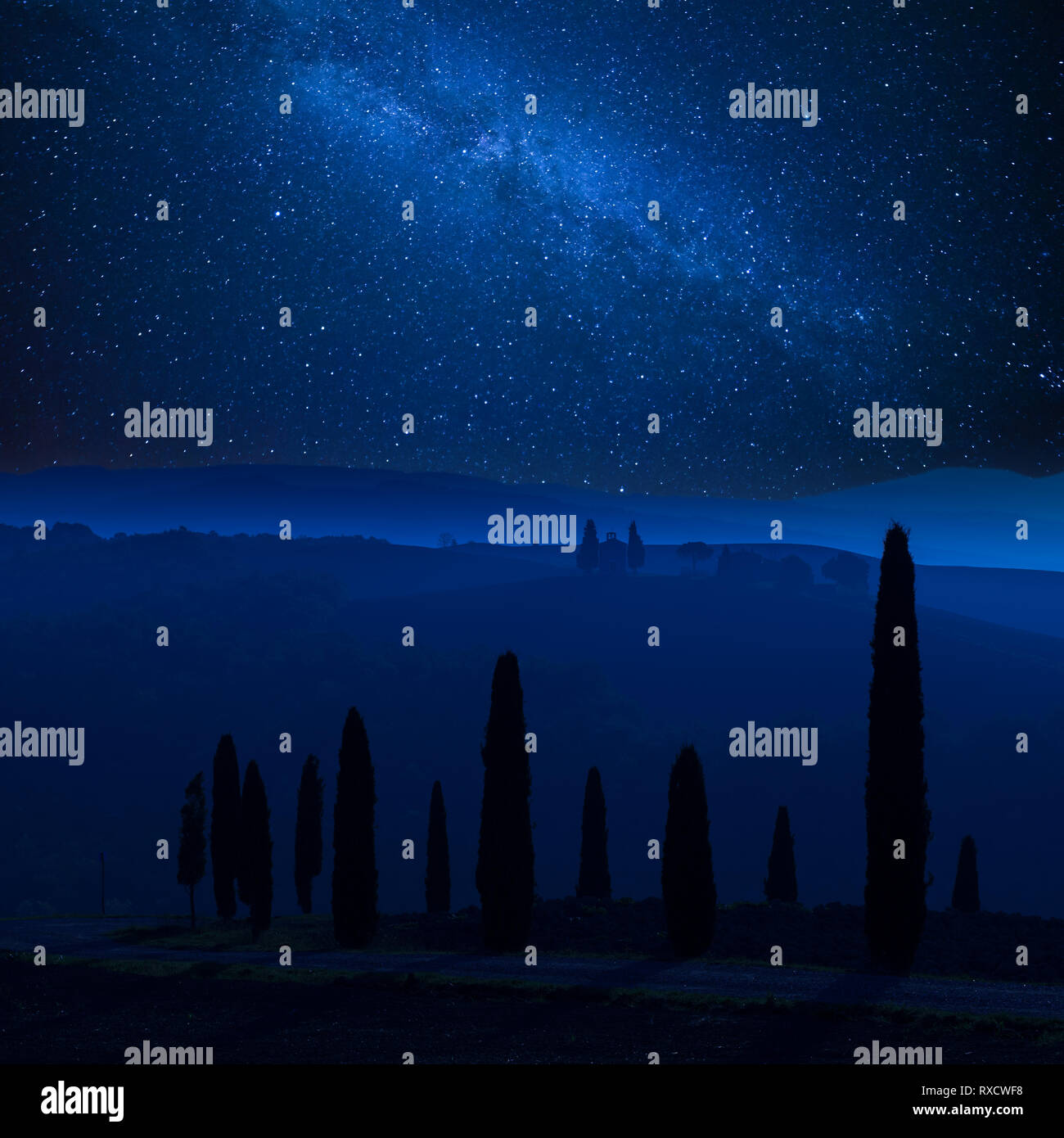 Night landscape with stars over cypress and Tuscany hills, milky way in sky Stock Photo