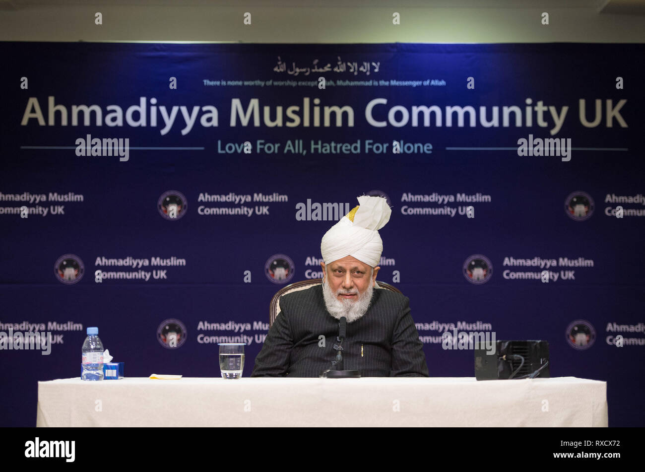 His Holiness Hazrat Mirza Masroor Ahmad speaks at a press conference during the National Peace Symposium, at the Baitul Futuh Mosque, in Morden, London. Stock Photo