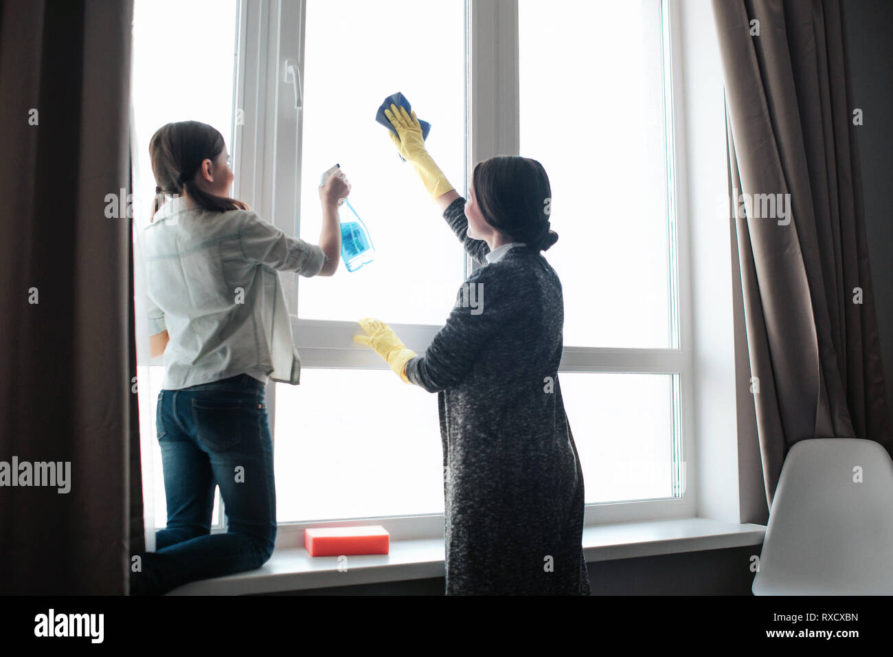 Beautiful brunette caucasian mother and daughter cleaning window ...