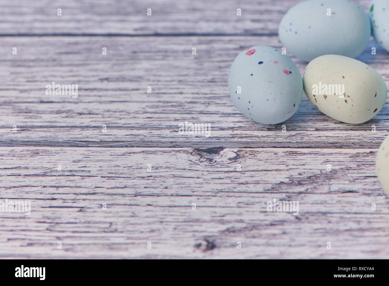 yellow and blue dragee eggs on a white wooden background, macro color photo Stock Photo