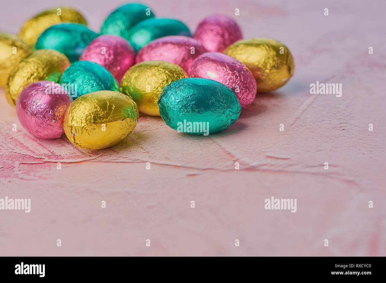 wrapped chocolate eggs on a pink background with copy space Stock Photo