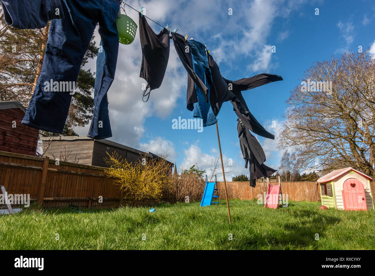 Clothes drying outside on a washing line on a windy day with broken clouds and a blue sky Stock Photo