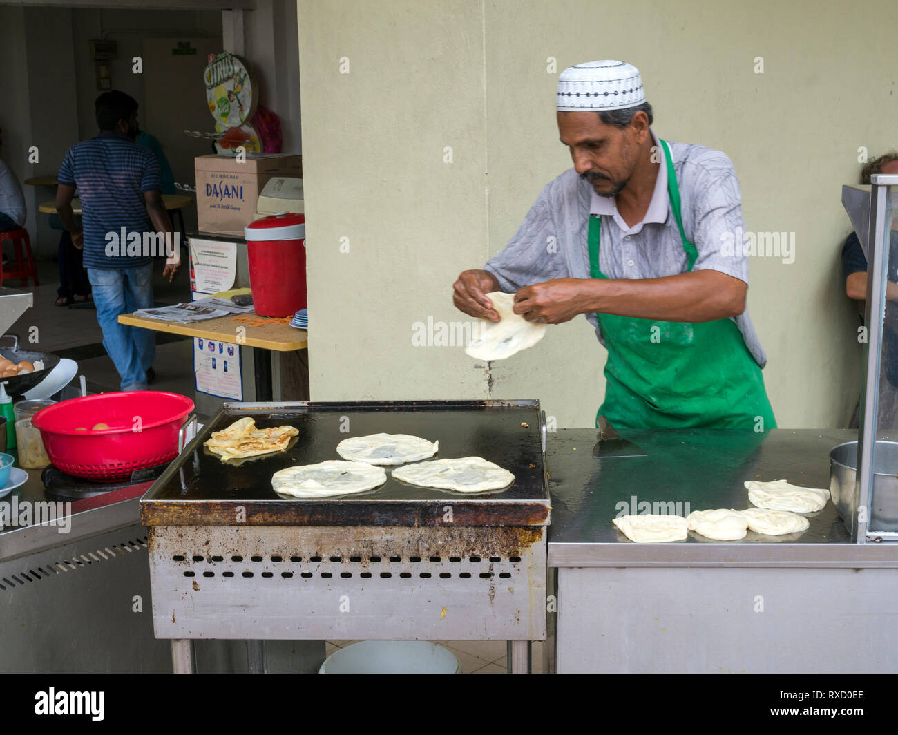 A man making roti cenai on a street corner in George Town, Penang. Roti Cenai is an Indian influenced thin bread cooked on a tava and served with dahl Stock Photo