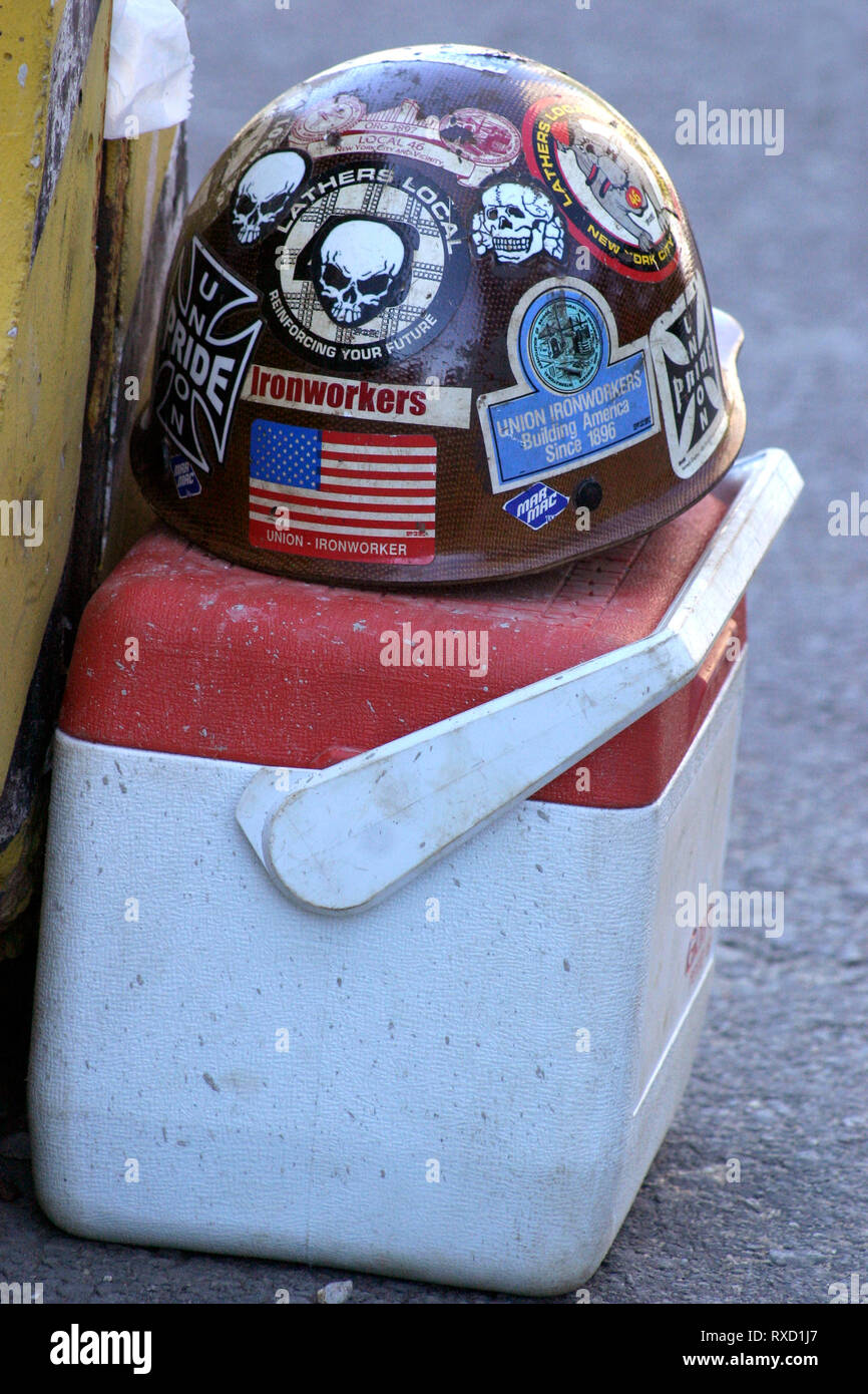 Worn hard hat covered in stickers and messages over a lunch box Stock Photo