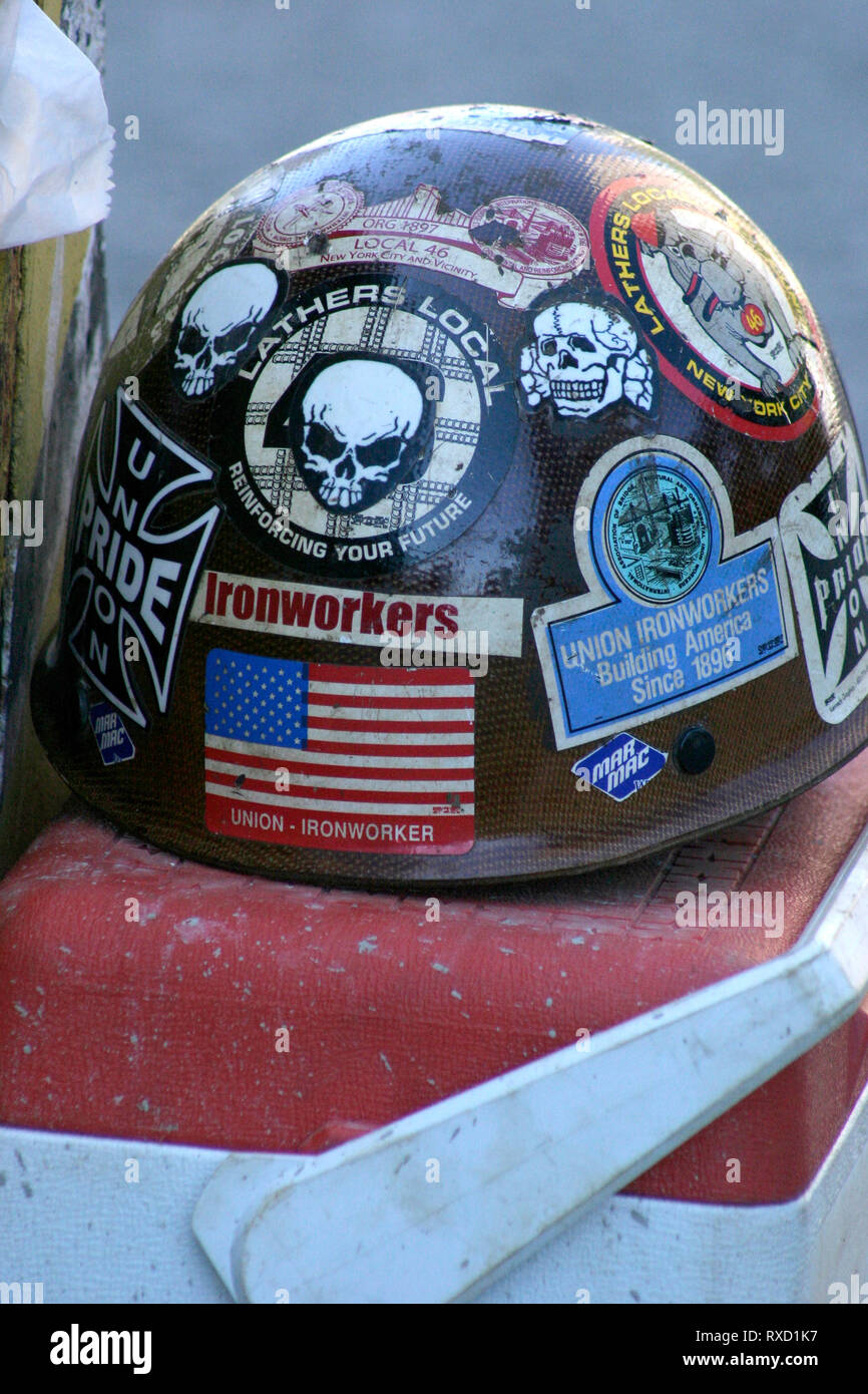 Worn hard hat covered in stickers and messages over a lunch box Stock Photo