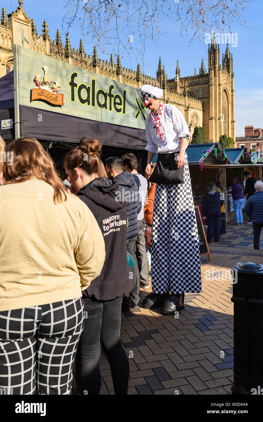 Super-sized chef (man on stilts) entertaining people looking at trade stalls - Wakefield Food, Drink & Rhubarb Festival 2019, Yorkshire, England, UK. Stock Photo