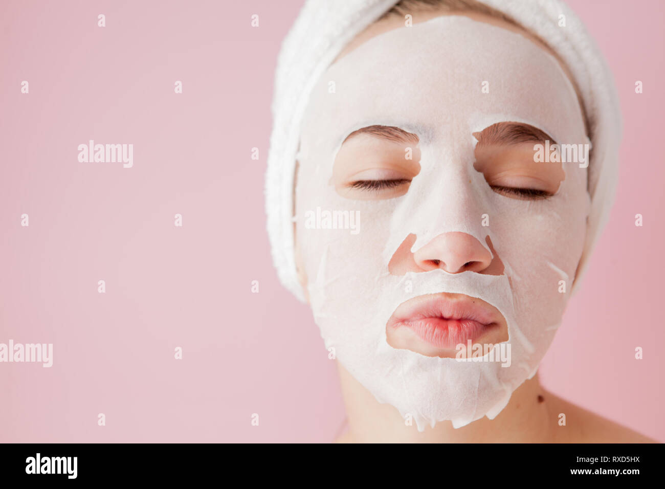 Beautiful young woman is applying a cosmetic tissue mask on a face on a ...